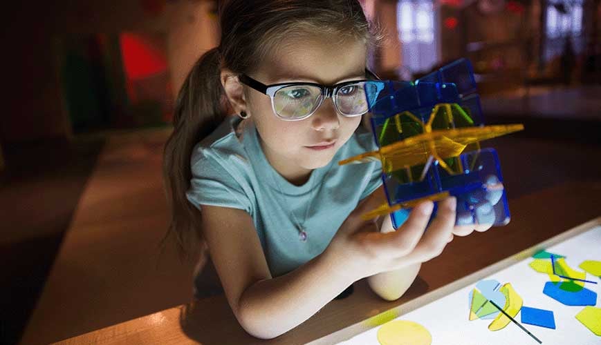 Curious Girl Holding Geometric Shape in Science Center