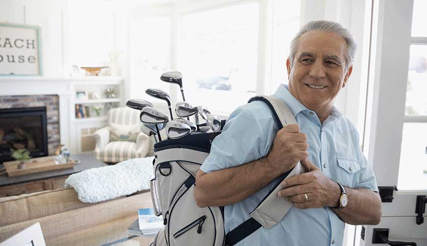 Senior male golfer carrying golf clubs