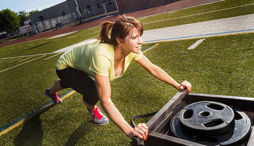 Woman pushing weighted sled for exercise